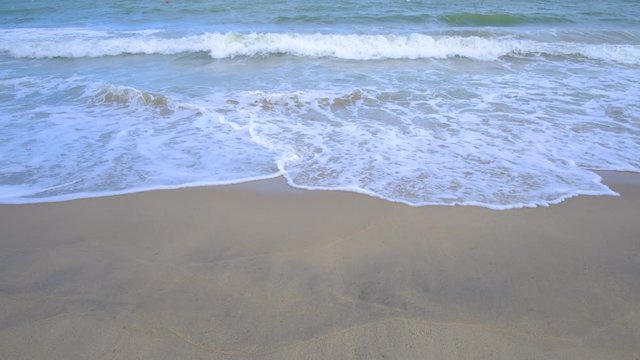 Beautiful background transparent surface wave, sand on clean seaside beach. Royalty high-quality free stock video footage of clean surface seawater, waves on the beach with sand and sunshine in summer