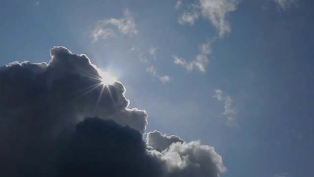 Bright sunlight rays appearing behind passing storm cloud