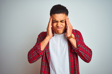 Young brazilian man wearing red shirt standing over isolated white background with hand on head for pain in head because stress. Suffering migraine.