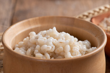 Cooked peeled barley grains in wooden bowl