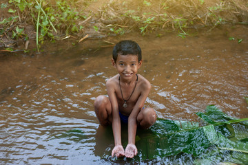A boy playing alone in a small stream in the countryside.