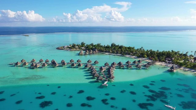 Travel vacation paradise aerial drone video with overwater bungalows in coral reef lagoon sea. Aerial video from Bora Bora, French Polynesia, Tahiti, South Pacific Ocean.