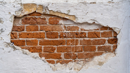 The cement wall has cracks. The inside is orange bricks.