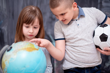 boy and little girl using globe of earth in front of chalkboard