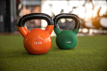 Orange and  green color kettle bells  on green artificial grass floors in the gym