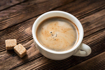 Cup of espresso and brown sugar on wooden table closeup view