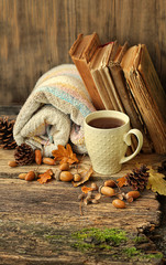 autumn composition with tea cup, warm sweater, old books, acorns and leaf on rustic wooden background. cozy fall season concept. sweater weather. scandinavian style, hugge. copy space. soft focus