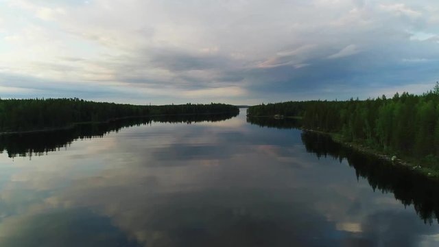 Northern river aerial scenes. Large wide river with islands covered with coniferous and mixed forests. Early morning, sun rises, clouds in the sky