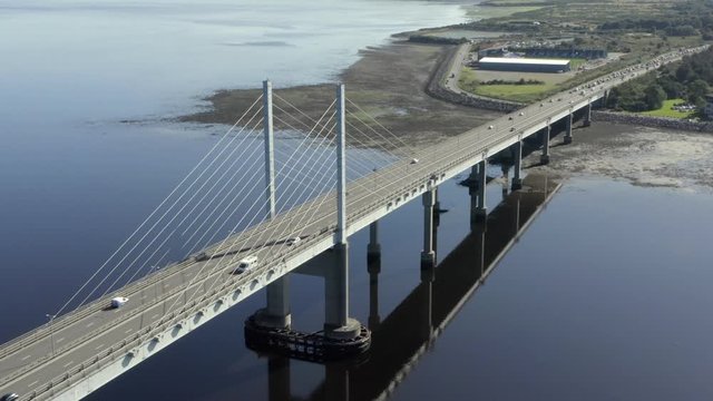 An aerial view of Kessock Bridge in Inverness on a sunny summer's morning. Rotating anti-clockwise around the western and southern side of the bridge whilst zooming in.