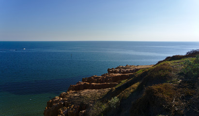 Fototapeta na wymiar Calm sea with cliffs and blue sky