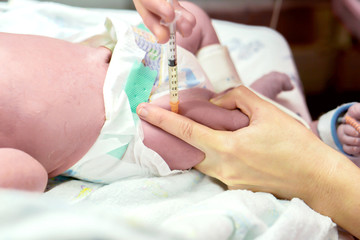 Image of a nurse hands is using a syringe gradually vaccinate on sick newborn baby's leg.