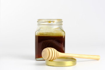 ็Honey dipper and Natural  honey in jar on white background.