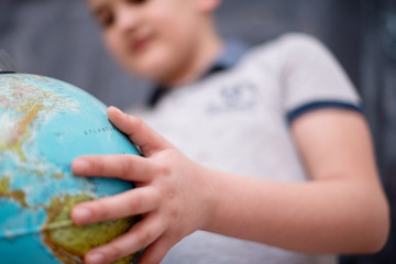 boy using globe of earth in front of chalkboard