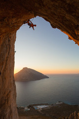 Silhouette of a climber in a cave above the Mediterranean sea with another island in view.. 