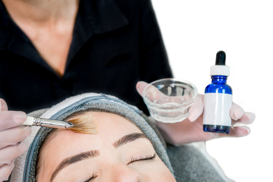 Close up of beautician (cosmetologist) applying chemical peel treatment on patient in a beauty spa, for skin rejuvenation, complexion and acne beauty treatments.