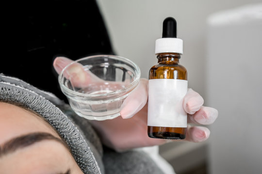 Close up of beautician (cosmetologist) applying chemical peel treatment on patient in a beauty spa, for skin rejuvenation, complexion and acne beauty treatments.