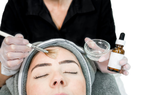 Close up of beautician (cosmetologist) applying chemical peel treatment on patient in a beauty spa, for skin rejuvenation, complexion and acne beauty treatments.