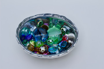 Silver color bowl containing glass pebbles and beads with Irish toasting phrases, 