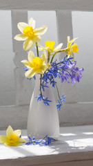 spring flowers in vase on white wooden bench