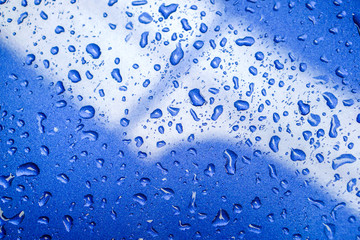 Top view background and texture of raindrops and reflection lighting on blue car engine hood.