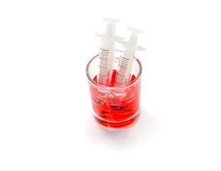 Red liquid medicine in medicine measuring glass cup with plastic syringes for ready to enter the patient mouth isolate on white background and make with paths.