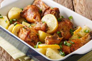 Chicken legs with lemon and boiled potatoes in garlic sauce close-up in a baking dish. horizontal