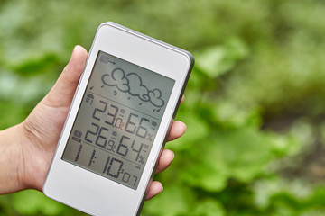 Best personal weather station device with weather conditions inside and outside. A girl holds a...