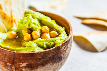 Avocado hummus in wooden bowl. Healthy vegan food concept.