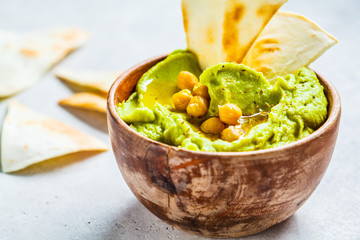 Avocado hummus in wooden bowl. Healthy vegan food concept.
