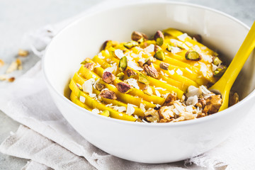Oatmeal with mango and nuts in white bowl. Healthy vegetarian food concept.