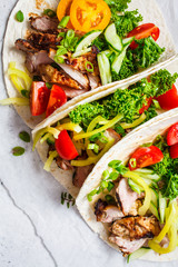 Healthy mini tortillas with grilled chicken, meat, fresh vegetables  on light grey background, top view.