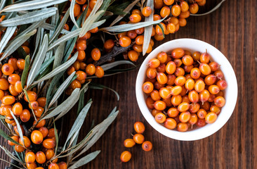  Leaves and berries of orange sea ​​buckthorn on wooden table background