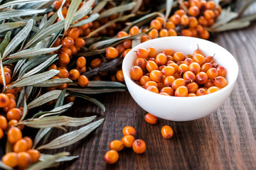  Leaves and berries of orange sea ​​buckthorn on wooden table background