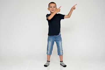 Full-length portrait on a white background of a cute boy child with Vitiligo disease - a violation of the color of the skin at the initial stage. Black T-shirt, blue jeans.