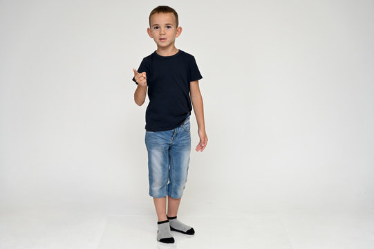 Full-length portrait on a white background of a cute boy child with Vitiligo disease - a violation of the color of the skin at the initial stage. Black T-shirt, blue jeans.