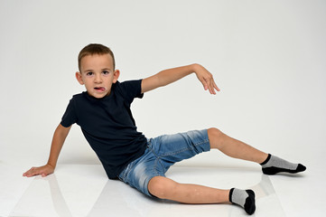 A full-length portrait of a cute boy child sitting on the floor on a white background with Vitiligo...