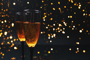 Two glasses of champagne on a black background with New Year's lights. Christmas concept. background for your new year design. new Year
