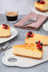 Classic cheesecake with berries and cup of espresso on gray background.