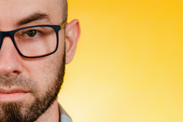 People and emotions. Portrait of a man with glasses and a beard, with a confident look. Close up. Yellow background