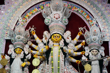 Goddess Durga idol at decorated Durga Puja pandal, shot at colored light, at Kolkata, West Bengal,...