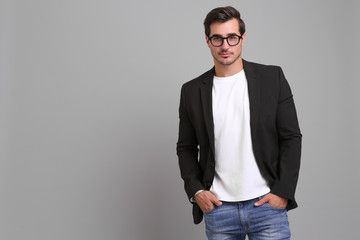 Handsome young man in casual clothes on grey background. Space for text