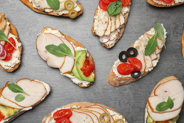 Different delicious chicken bruschettas on grey table, flat lay