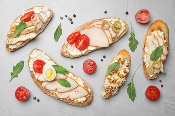 Different delicious chicken bruschettas on light grey table, flat lay