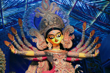 Goddess Durga idol at decorated Durga Puja pandal, shot at colored light, at Kolkata, West Bengal,...