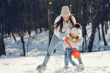 young and stylish mom with long dark hair playing with her little cute daughter in winter snow park