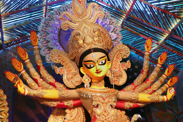 Goddess Durga idol at decorated Durga Puja pandal, shot at colored light, at Kolkata, West Bengal,...