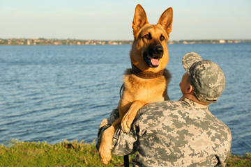 Man in military uniform with German shepherd dog outdoors