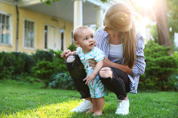 Teen nanny with cute baby on green grass outdoors