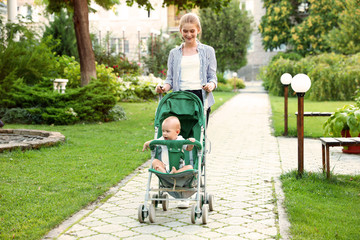 Teen nanny with cute baby in stroller walking in park