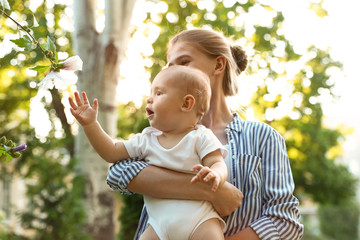 Teen nanny with cute baby in park on sunny day